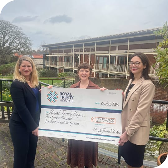 3 women standing in the garden, holding a big check