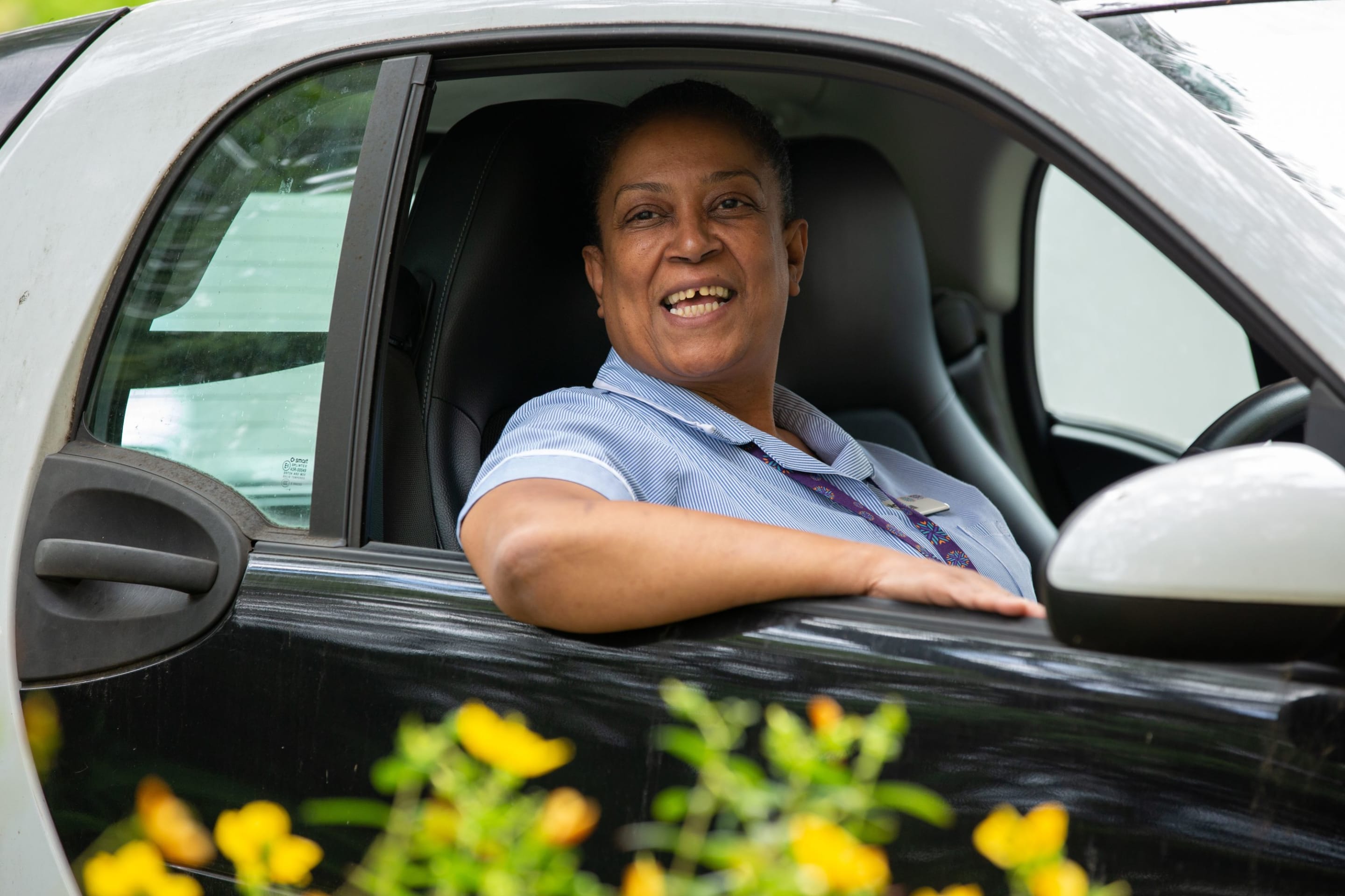 Woman sitting in her car smiling in a nurses uniform