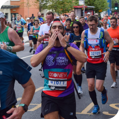 A man running the London Marathon, wearing a Royal Trinity Hospice T-Shirt