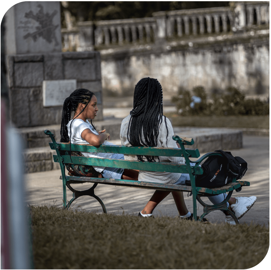 2 girls sitting on a bench talking