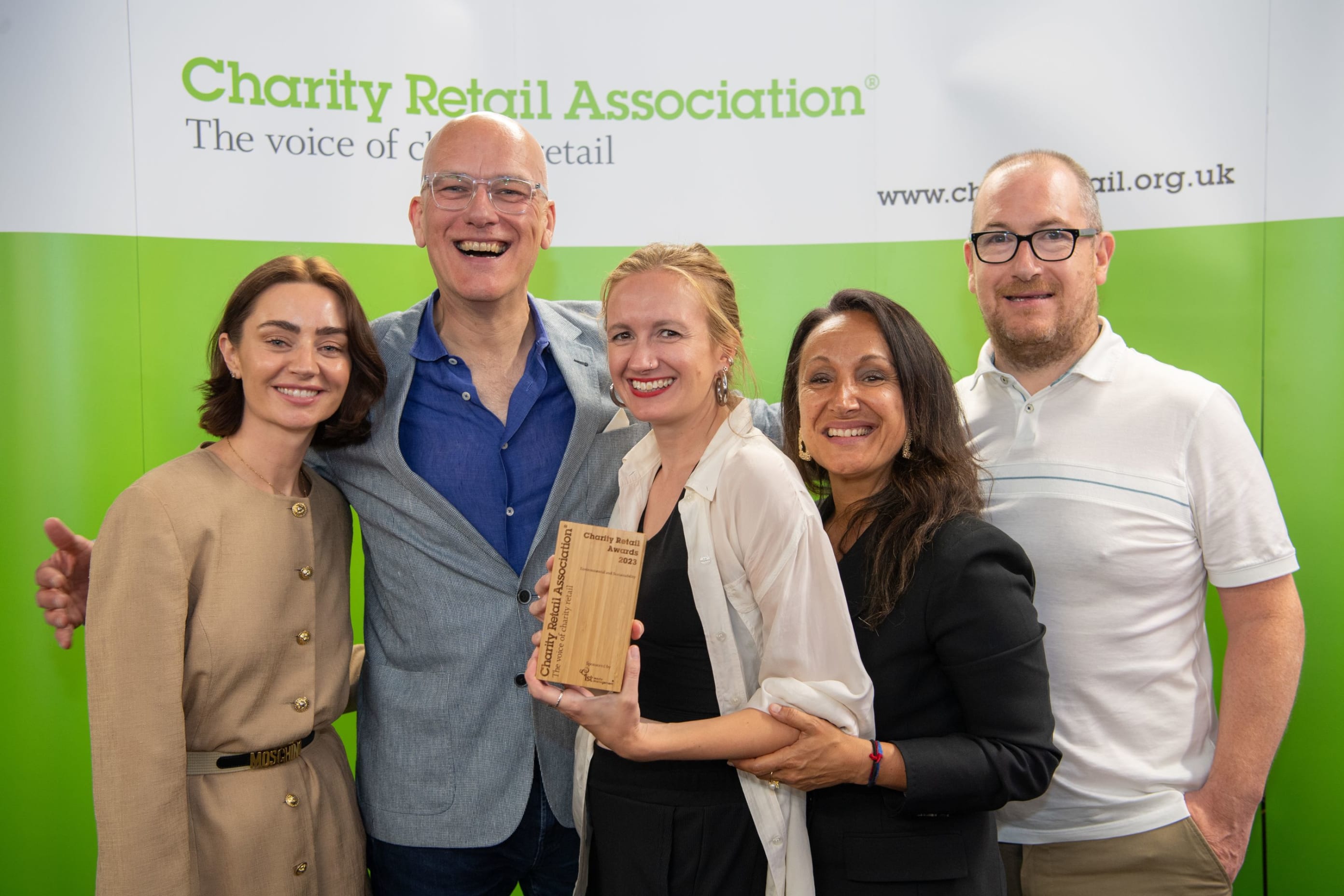 3 women and 2 men stood smiling, holding an award