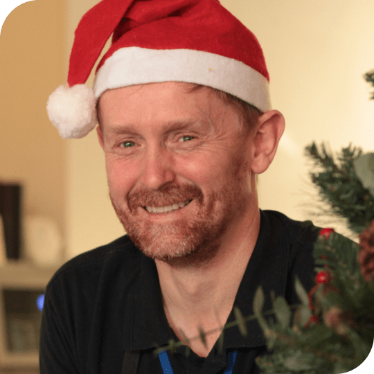 A man smiling wearing a santa hat