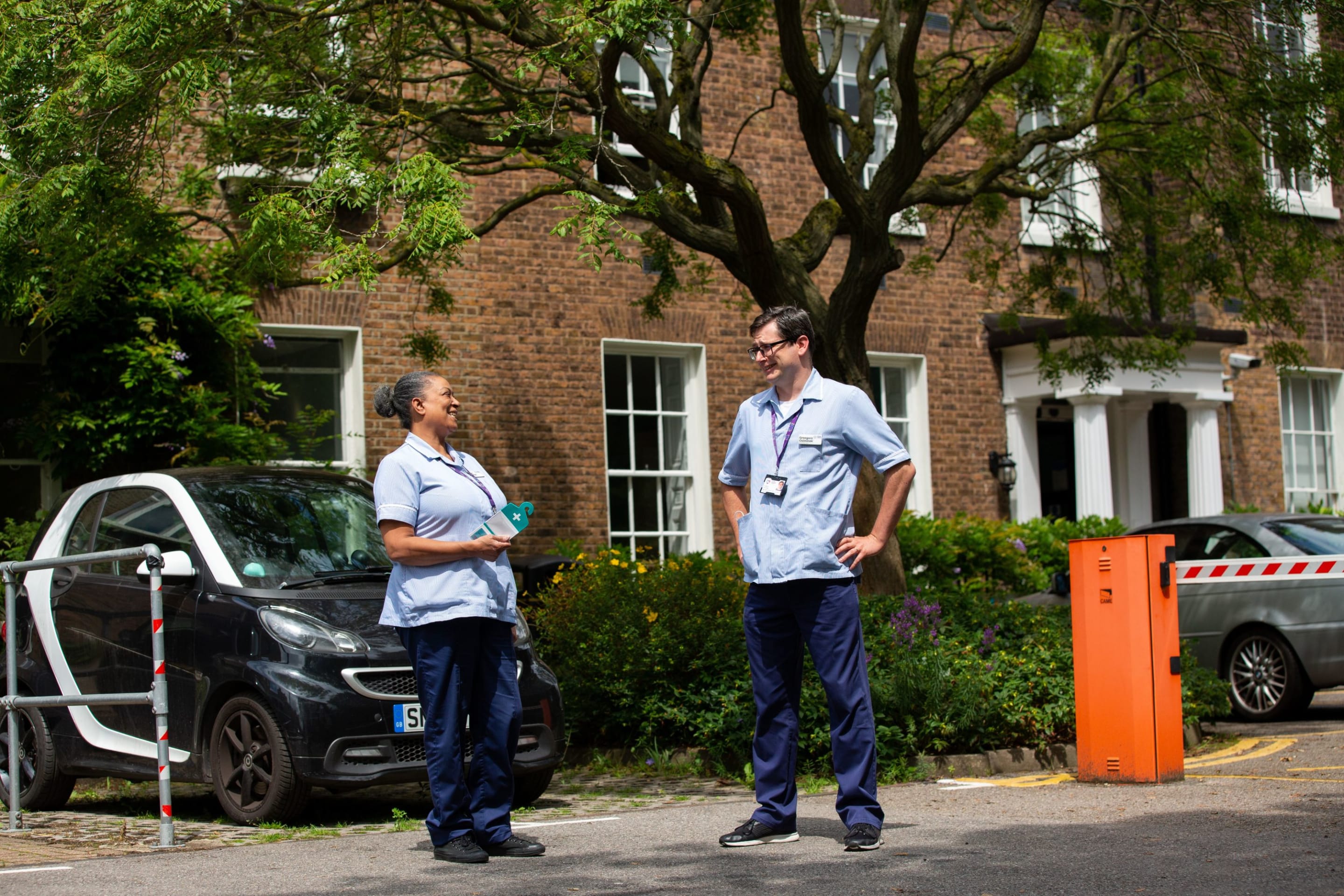 A male and female nurse standing outside a building chatting