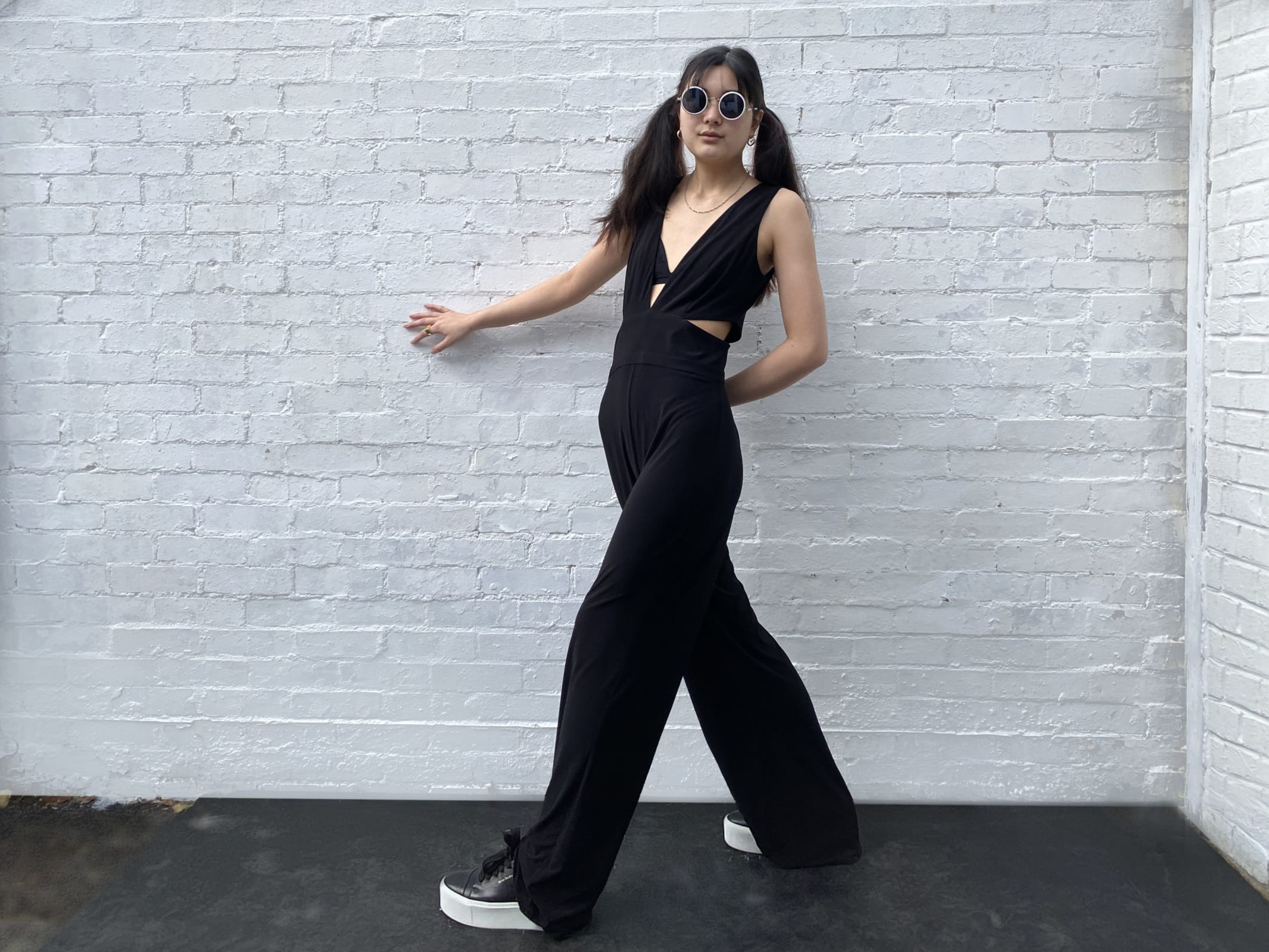 Girl in a black jumpsuit with black glasses on